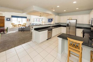 A spacious kitchen with white cabinetry, a central island, and a stainless steel refrigerator. - Southside, 2-level condo with big ocean views, balcony, WiFi & on-site pool/gym (Virginia Beach)