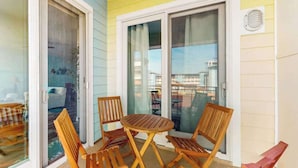 Ein Balkon mit Tisch, Stühlen, Glastüren und Blick auf Gebäude.