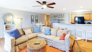 Un salon avec un canapé, une table basse et un ventilateur de plafond.