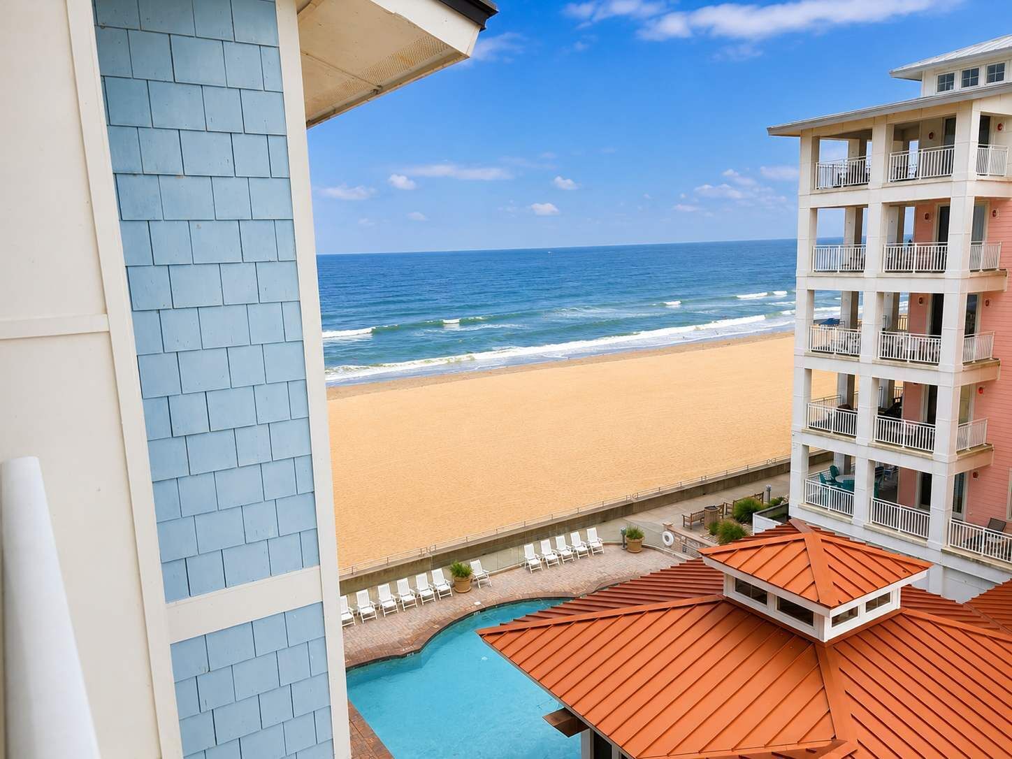 A hotel with a pool, beach view, and multiple balconies.
