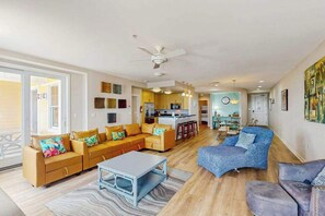 A spacious living area with a sofa set, a coffee table, and a blue armchair. - Superb oceanfront condo with beachfront balcony, 3 pools, & grills (Virginia Beach)