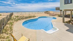 A swimming pool with a wooden deck, beach view, and a covered area with chairs. - Oceanfront home w/private pool, beautiful views, WiFi, central AC, private W/D (Virginia Beach)