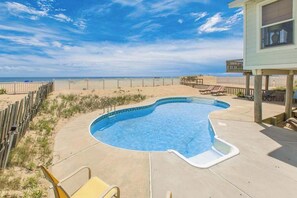 A swimming pool with a wooden deck, beach view, and a covered area with chairs. - Oceanfront home w/private pool, beautiful views, WiFi, central AC, private W/D (Virginia Beach)