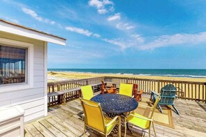 A wooden deck with a round table and chairs, overlooking a beach. - Oceanfront home w/private pool, beautiful views, WiFi, central AC, private W/D (Virginia Beach)