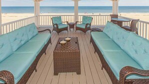 A covered outdoor seating area with wicker furniture and a view of the beach. - Oceanfront vacation gem w/private indoor & outdoor pools, WiFi, central AC, W/D (Virginia Beach)