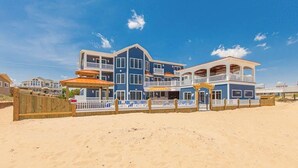 A beachfront property with multiple balconies, a wooden fence, and a clear blue sky. - Oceanfront vacation gem w/private indoor & outdoor pools, WiFi, central AC, W/D (Virginia Beach)