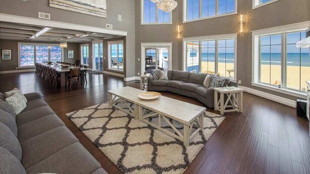 A spacious living area with a large window overlooking the beach, a dining area with a view, and a cozy seating area with a fireplace. - Oceanfront vacation gem w/private indoor & outdoor pools, WiFi, central AC, W/D (Virginia Beach)