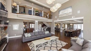 A spacious living area with a fireplace, a sofa, a dining table, and a staircase leading to an upper level. - Oceanfront vacation gem w/private indoor & outdoor pools, WiFi, central AC, W/D (Virginia Beach)