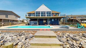A beachfront property with a swimming pool, wooden deck, and a building with a balcony. - Wonderful home on the bay with private dock and pool, WiFi, washer/dryer (Virginia Beach)