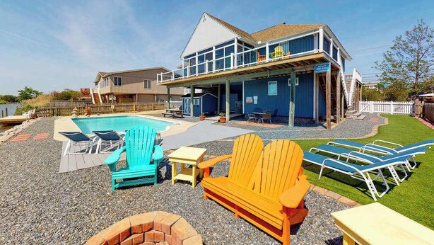 A two-story house with a pool, outdoor seating, and a covered patio area. - Wonderful home on the bay with private dock and pool, WiFi, washer/dryer (Virginia Beach)