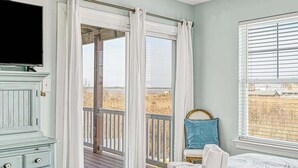 A bedroom with a bed, a TV, a dresser, a window with blinds, and a view of the outdoors. - 9BR home with private pool, hot tub & 4 min to beach, free WIFI (Virginia Beach)