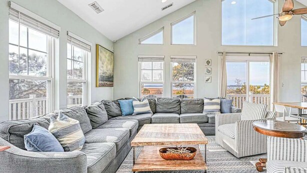A spacious living room with a large sectional sofa, a coffee table, and a striped armchair. - 9BR home with private pool, hot tub & 4 min to beach, free WIFI (Virginia Beach)
