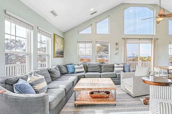 A spacious living room with a large sectional sofa, a coffee table, and a striped armchair.