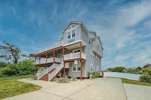 A two-story house with a balcony, a staircase, and a sign indicating a beach address.