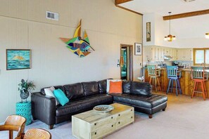 A living room with a black leather sofa, wooden coffee table, and colorful chairs. - Oceanfront home w/ocean views, WiFi, central AC, balcony, deck, washer/dryer (Virginia Beach)