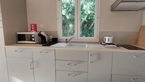 Una cocina equipada con microondas, hervidor y pileta.