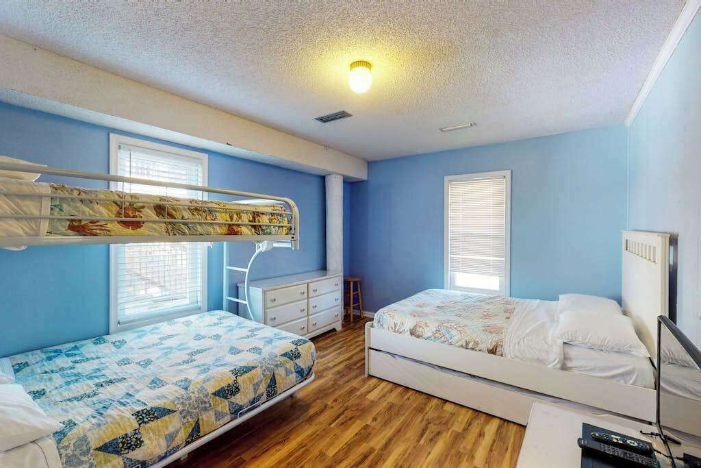 A room with bunk beds, a desk, and a window.