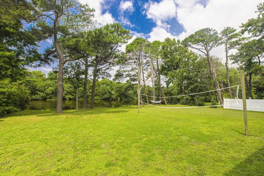 A grassy outdoor area with a hammock and a volleyball net.