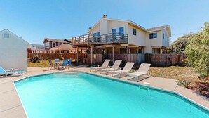 Une maison à deux étages avec une piscine, une terrasse couverte et un jardin clôturé.