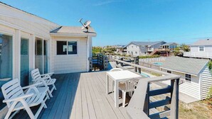 Une terrasse dotée de mobilier d’extérieur, d’une piscine et offrant une vue sur les maisons voisines.