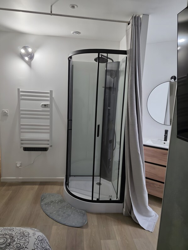 Une salle de bain moderne avec une douche à parois de verre, un porte-serviettes et un plancher en bois.