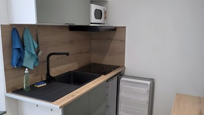 A compact kitchen with a built-in microwave, a sink, and a small refrigerator.