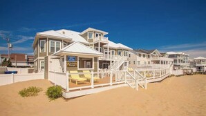 Ein Strandgrundstück mit einem großen Haus, einer überdachten Terrasse und einem Sandstrand.