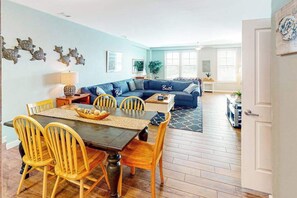 Ein Essbereich mit Holztisch und -stühlen, einem blauen Sofa und dekorativen Wandbildern.