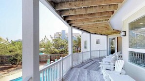 Eine überdachte Terrasse im Freien mit weißen Stühlen und einem Pool.