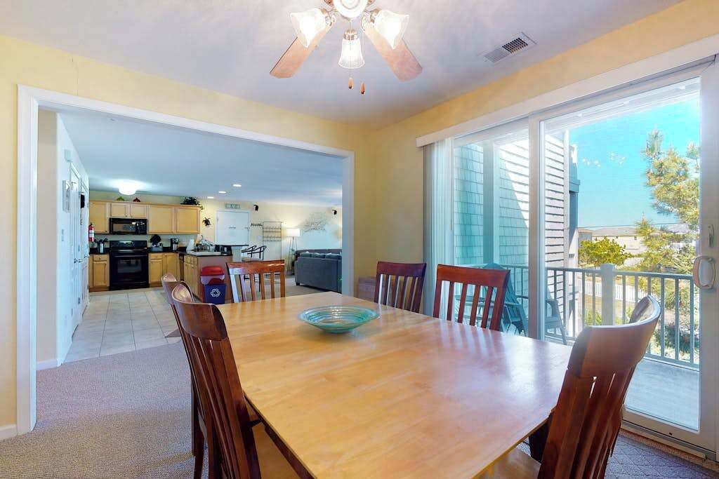 Un comedor con una mesa y sillas de madera, un ventilador de techo y vistas al exterior.