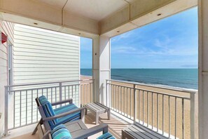 A balcony with a view of the ocean, a bench, and a small table. - Oceanfront corner condo with amazing balcony views, outdoor pool & gym (Virginia Beach)