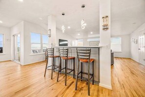 A modern kitchen with a central island, bar stools, and pendant lighting.