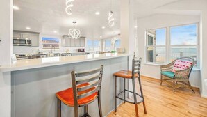 A modern kitchen with a central island, bar stools, and pendant lighting. - Spacious beach house with indoor pool, hot tub, & multiple decks (Virginia Beach)