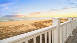 A beach view from a white wooden deck with a railing. - Spacious beach house with indoor pool, hot tub, & multiple decks (Virginia Beach)