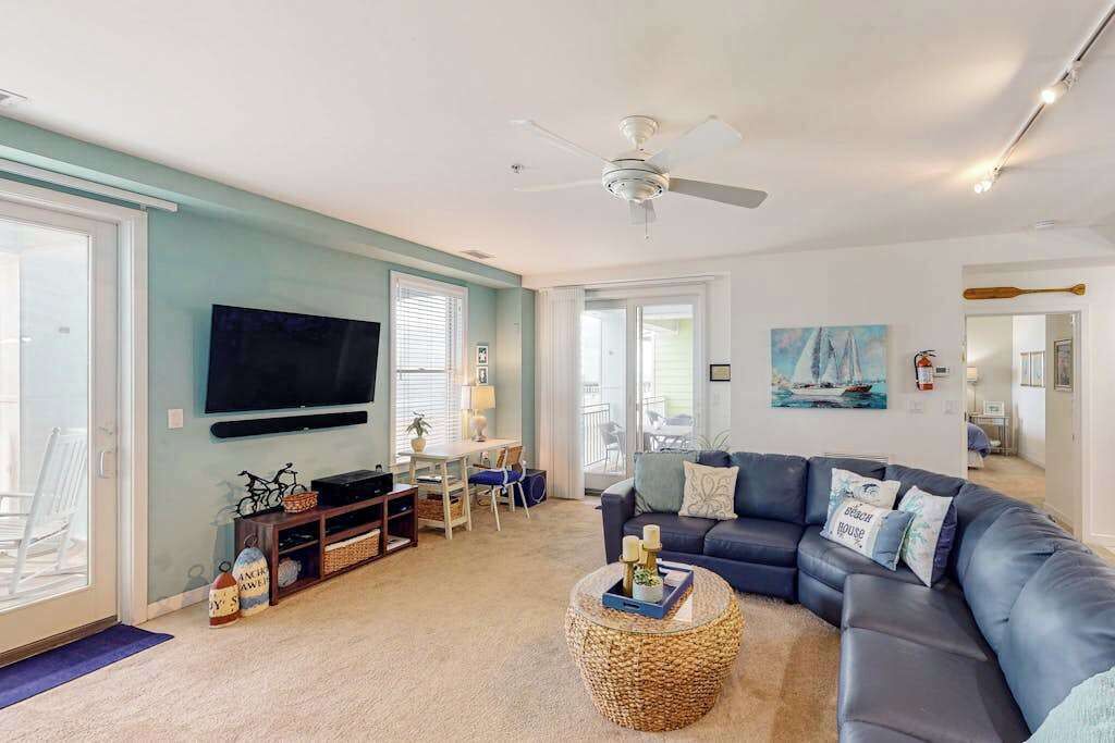 A living room with a television, sofa, coffee table, and a ceiling fan.