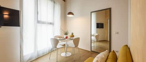 A modern living room with a wooden ceiling, a sofa, a dining table with chairs, and a large mirror.