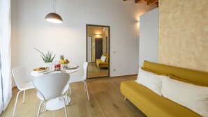 En moderne stue med sofa, spisebord, stole og et spejl.
