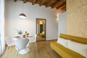 A modern living room with a sofa, dining table, chairs, and a mirror. - Cesariano, 11 - Downtown - Park & Movida (Milan)