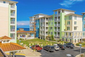 A multi-story hotel with balconies, a parking lot, and a view of the ocean. - Top-floor corner courtyard home with pool, gym, & game system (Virginia Beach)