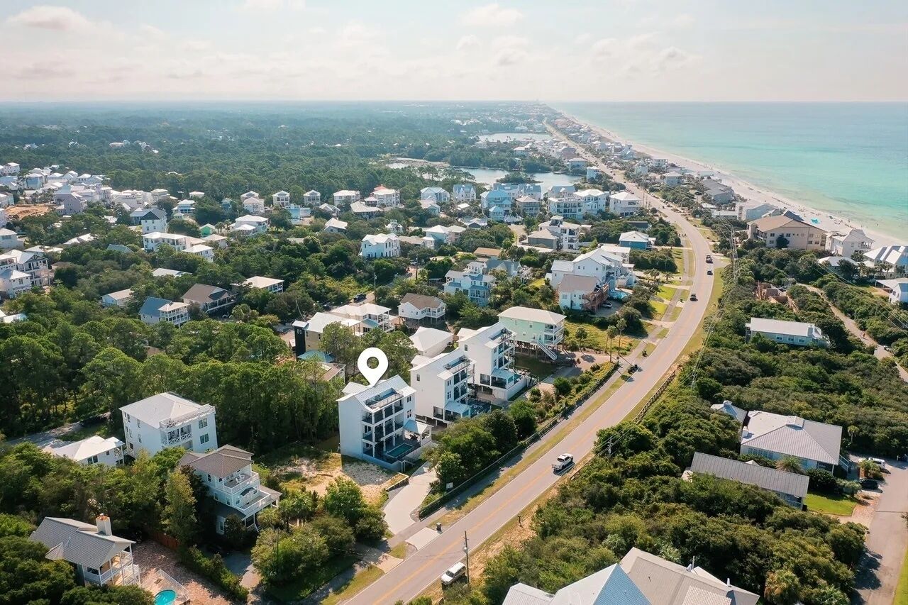 Vista aérea de una zona residencial costera con casas, una playa y una carretera.