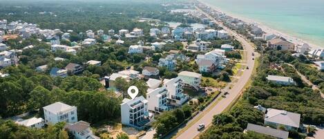 Vista aérea de una zona residencial costera con casas, una playa y una carretera.