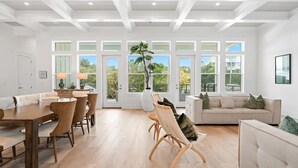 A spacious living area with a dining table, sofas, and a large window with a view of greenery. - 🐚Private Pool | Golf Cart | Steps to Beach | Gulf Views | 30A All Day (Santa Rosa Beach)