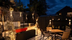 Eine Terrasse mit gefliestem Boden, einem Holztisch und Stühlen.