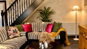 Ein Wohnzimmer mit gepolstertem Sofa, einer Treppe, einem Heizkörper und einer Lampe.