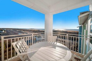Ein Balkon mit Tisch und Stühlen, der auf eine Küstenlandschaft blickt.