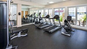 A gym with treadmills, a bench press, and a weight machine. - Beachfront condo with 2 oceanfront balconies, W/D, pool, & gym (Virginia Beach)