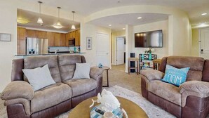 A living room with two sofas, a coffee table, and a TV. - Comfortably furnished condo with glimpses of Back Bay, pool & gym (Virginia Beach)