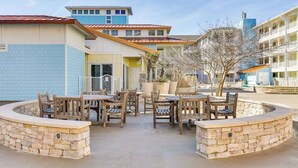 A courtyard with outdoor seating, stone walls, and a building with multiple floors and balconies. - Comfortably furnished condo with glimpses of Back Bay, pool & gym (Virginia Beach)