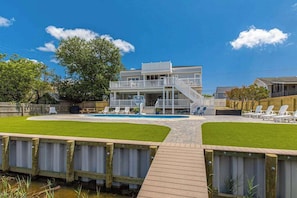 A two-story building with a pool, a wooden deck, and outdoor seating. - Lovely canal-front home between bay & beach with private pool, dock, & AC (Virginia Beach)