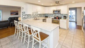 Una cocina moderna con una isla grande, armarios blancos y un salpicadero de azulejos.